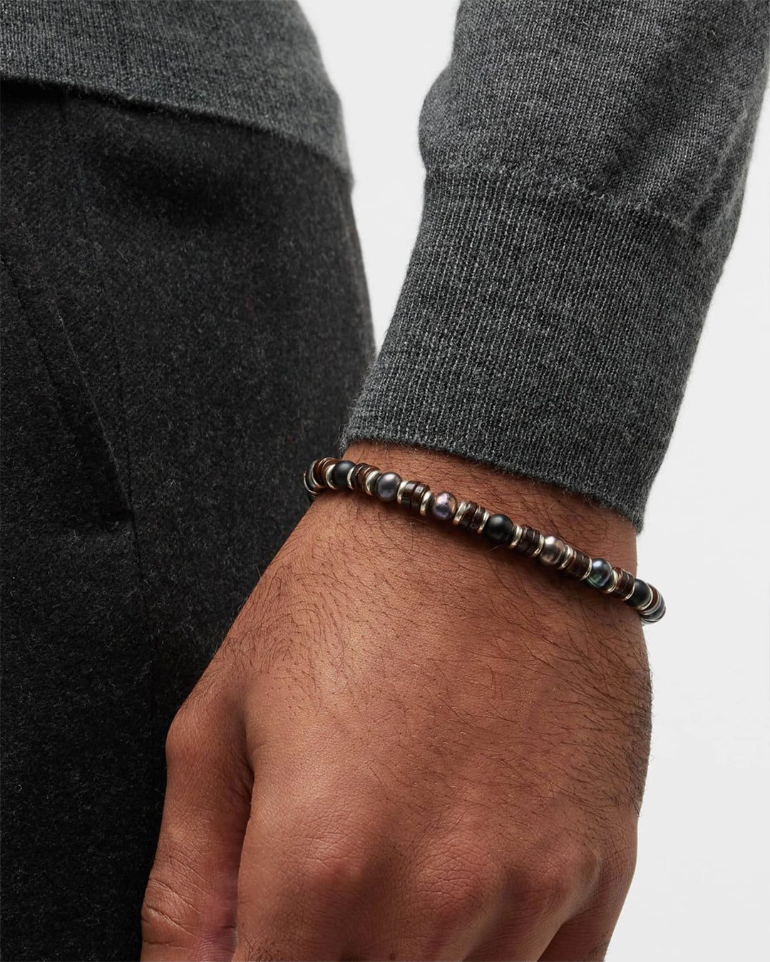 Close up photo of a male models wrist wearing the Grey Freshwater Pearl and Black Agate Beaded Bracelet. 