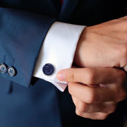 Man in navy suit adjusting white French cuff dress shirt wearing hand-carved deep navy blue goldstone rose cufflink with spiral petal detail on cuff, Jan Leslie 