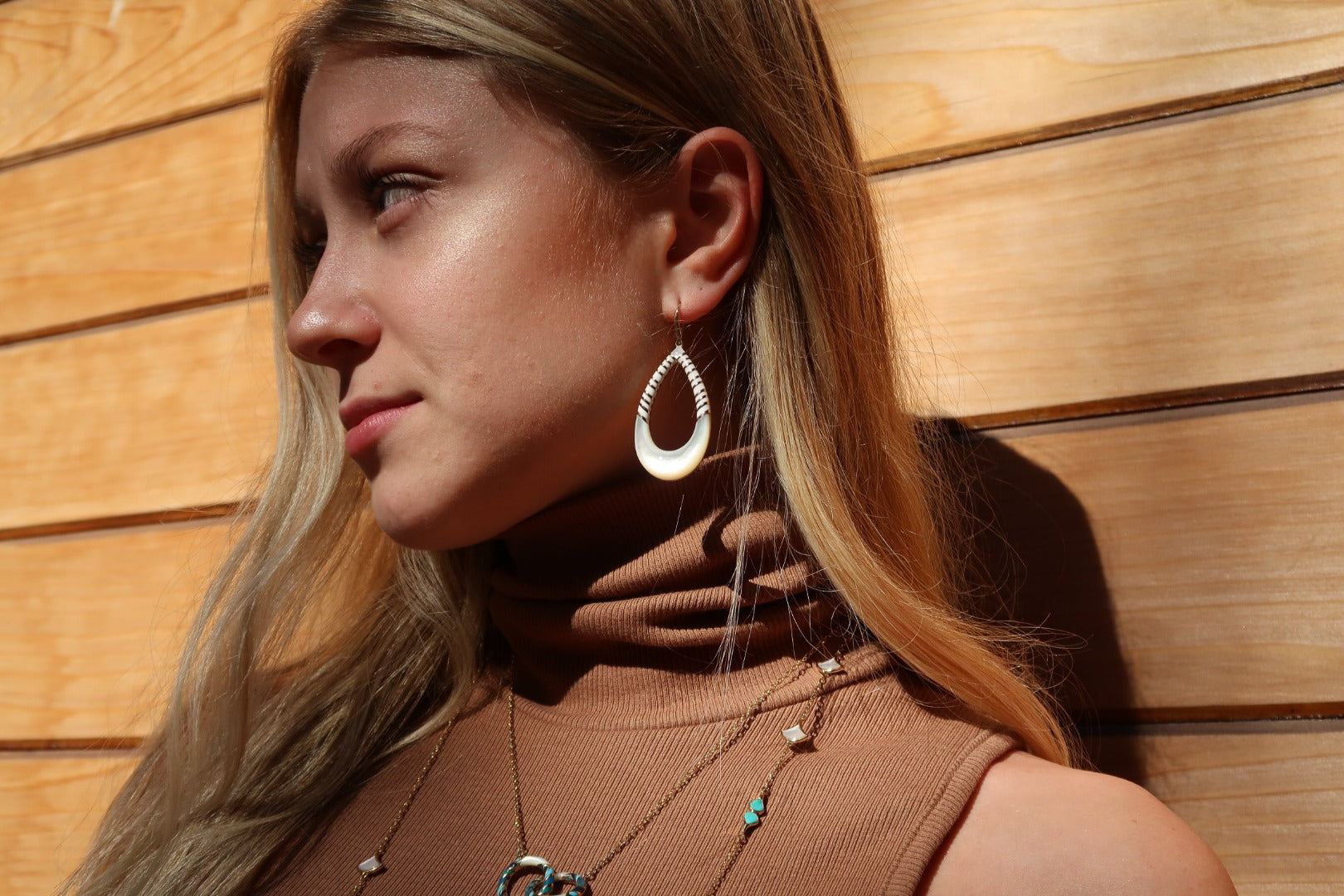 Close up of model wearing the Stripe Enamel and Mother of Pearl Gemstone Teardrop 18K Gold Vermeil Sterling Silver Earrings in white on gold from Jan Leslie's Stripe Collection. 