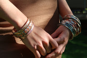 Mother of pearl and multicolor enamel sterling silver bangles stacked on model's wrist