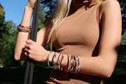 Mother of pearl and multicolor enamel sterling silver bangles stacked on model's wrist