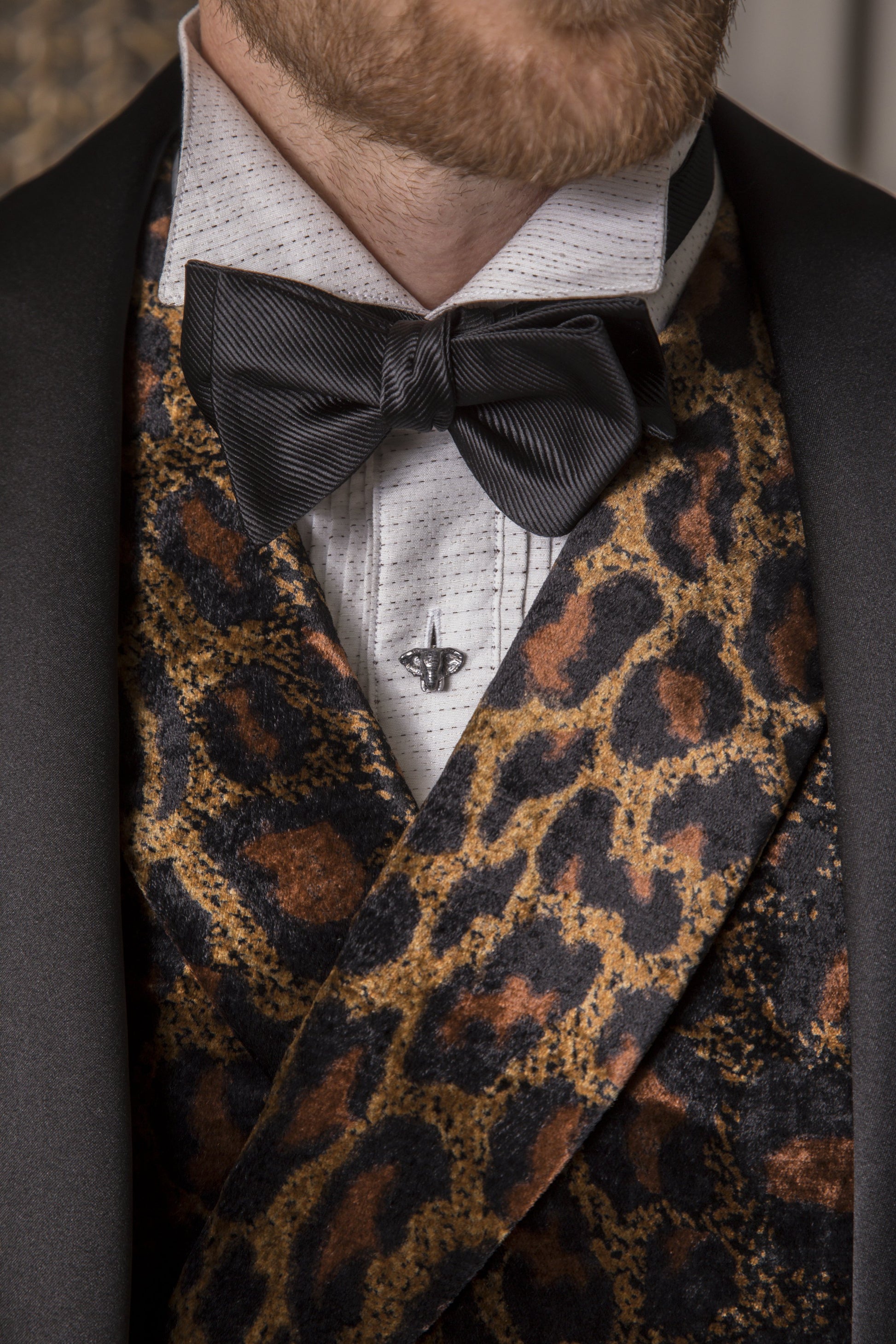 Close up of male models torso showing off a Elephant Head Mother of Pearl & Enamel Sterling Silver Tuxedo Stud on a patterned white tuxedo shirt. 