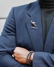 Male model wearing Moving Skier Sterling Silver Lapel Pin on a navy blue suit jacket. 