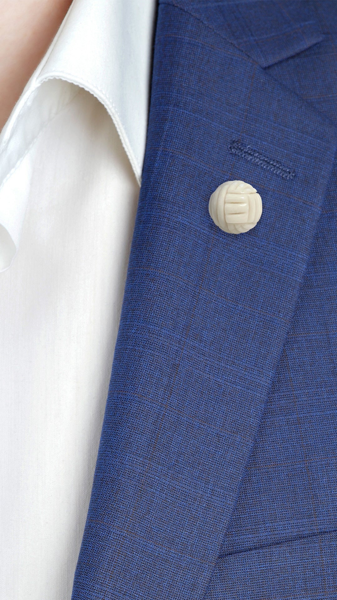 Male model wearing Hand-Carved Mystical Knot Gemstone Sterling Silver Lapel Pin with Chain on a navy blue suit jacket. 