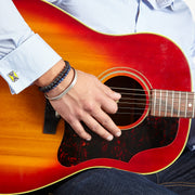 Close up of male models wrist wearing Corvette Fordite Sterling Silver Cufflinks in yellow on a light blue cuffed shirt.