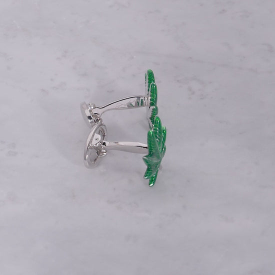 360 video of sterling silver and green enamel cannabis leaf cufflinks on marbled background. 