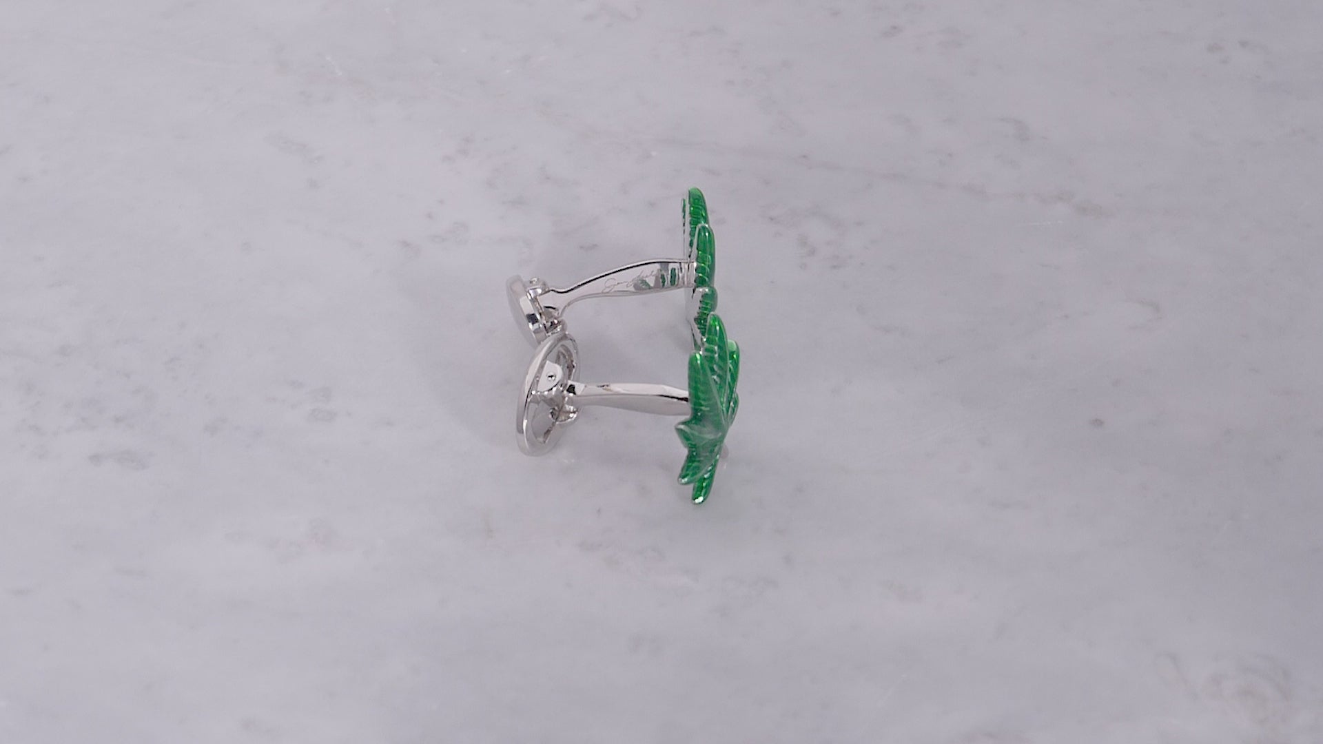 360 video of sterling silver and green enamel cannabis leaf cufflinks on marbled background. 